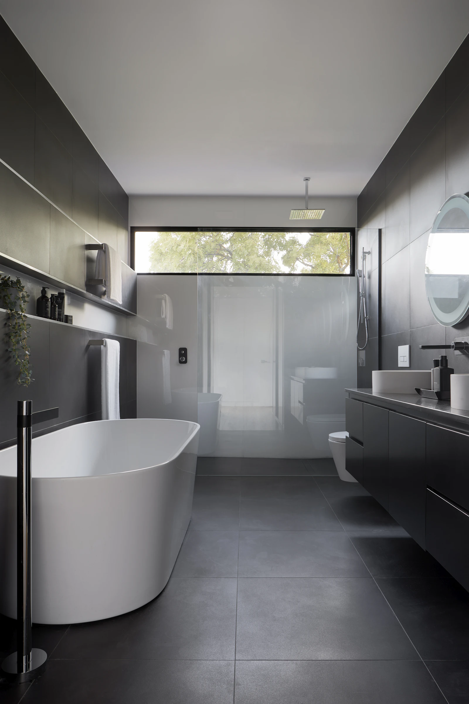 Modernes Badezimmer mit freistehender Wanne und dunklen Fliesen